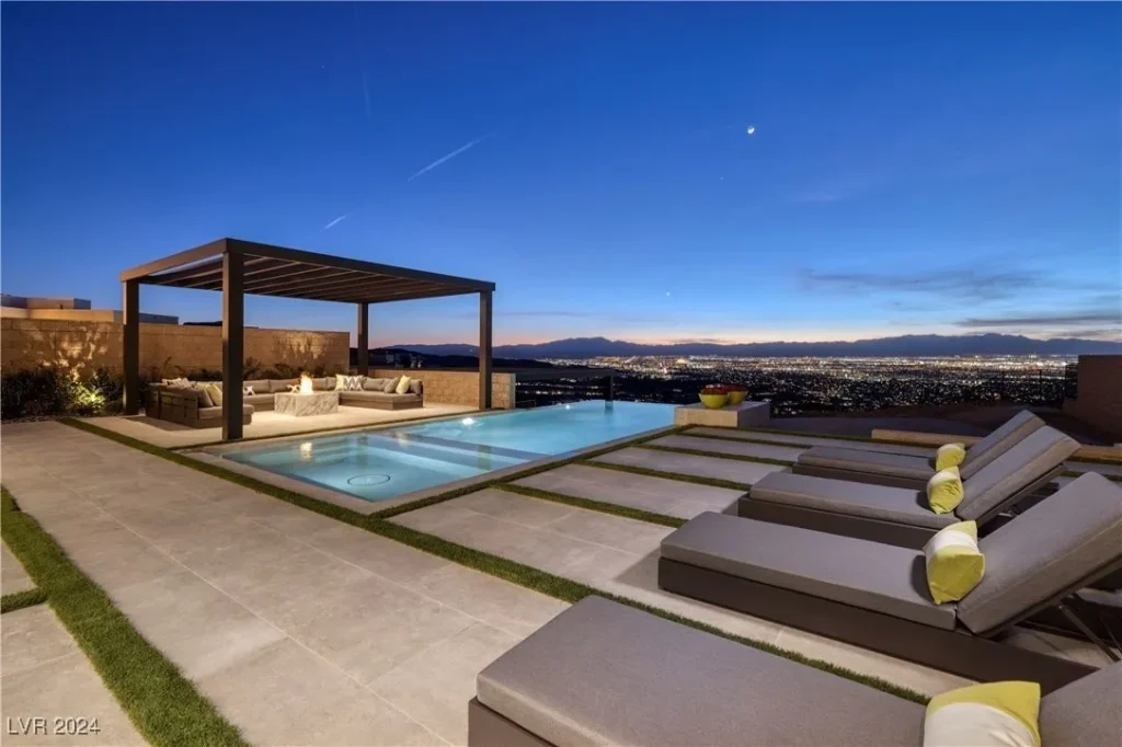 The backyard deck with lounge chairs and an infinity-edge pool overlooking the Las Vegas skyline